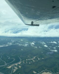 Looking under the wing at cloud building over winding rivers on the floodplains.